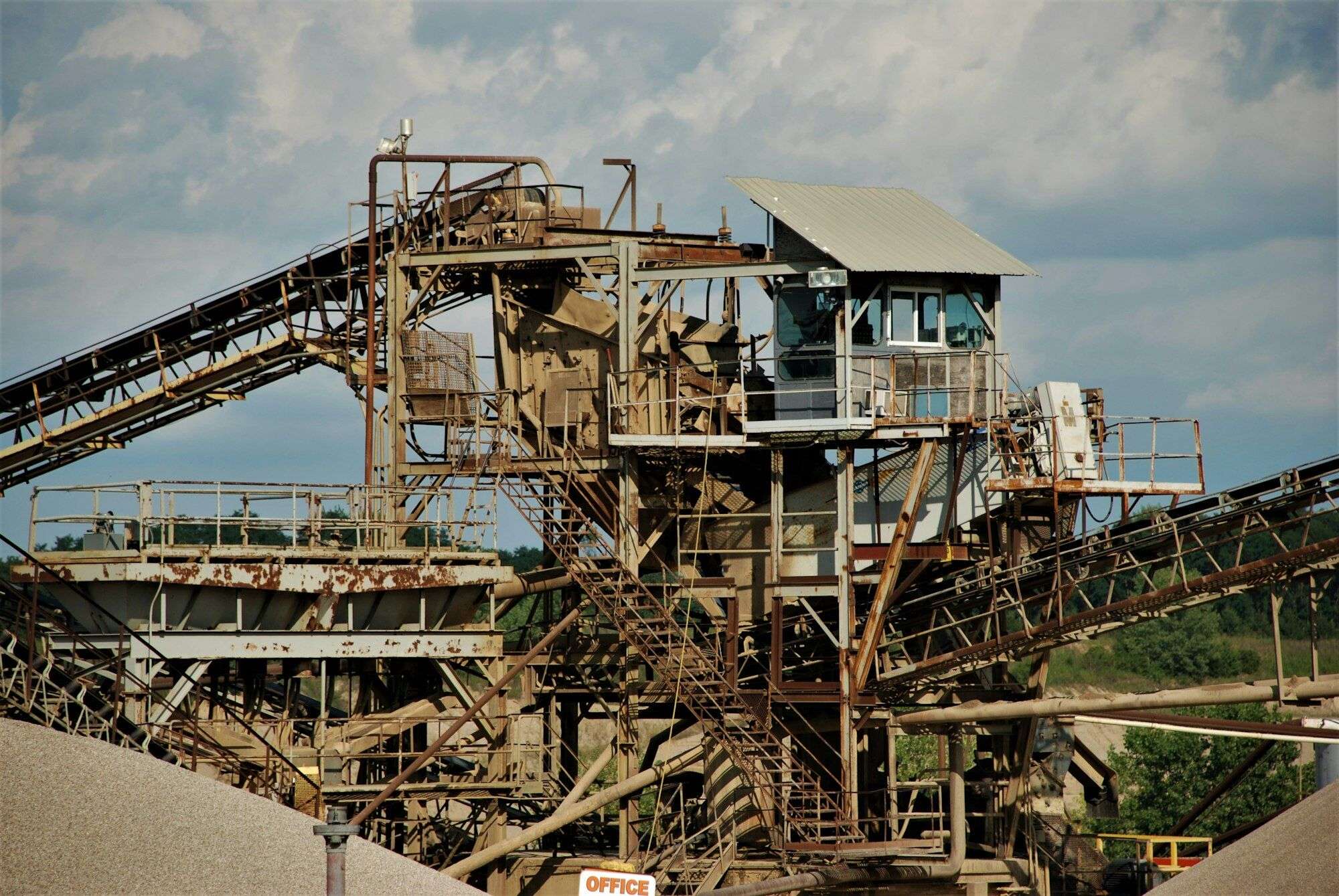 Crushing and screening plant at a gravel quarry, with crusher feed conveyors, screen decks and an elevated control cabin