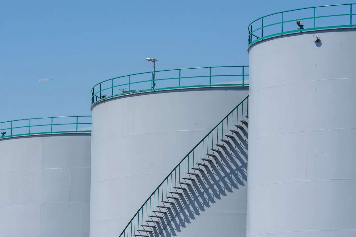 Large white bulk fuel storage tanks with stairs