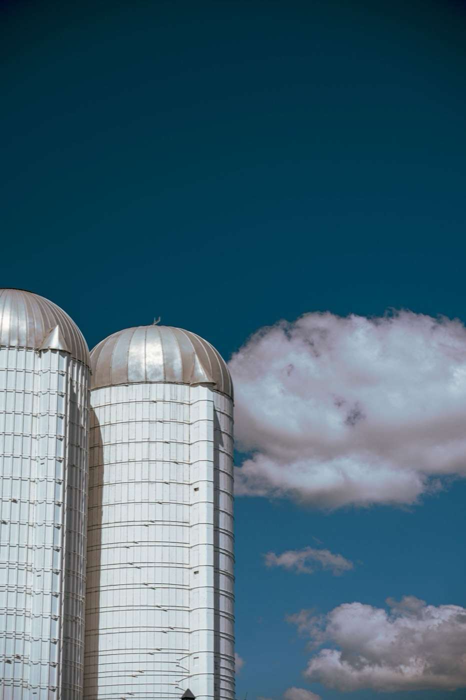 Tops of two galvanised steel silos against a blue sky
