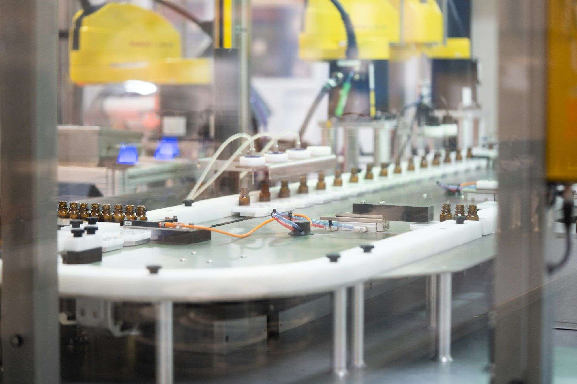 Automated bottle filling machine with filling nozzles above small bottles on an indexing conveyor