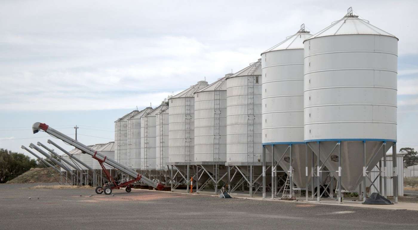 Row of steel grain silos with a grain auger at a country site