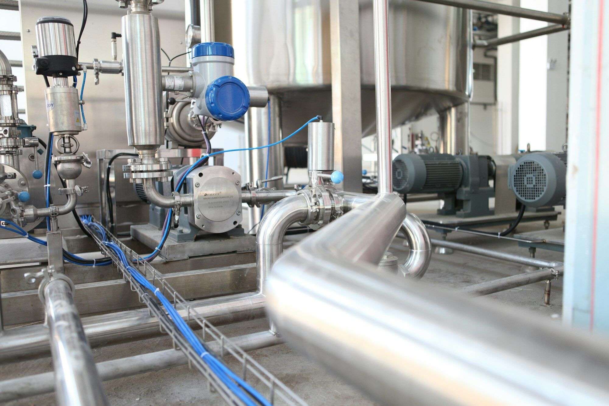 Stainless process pipework, valves and motor-driven pumps in a food and beverage plant