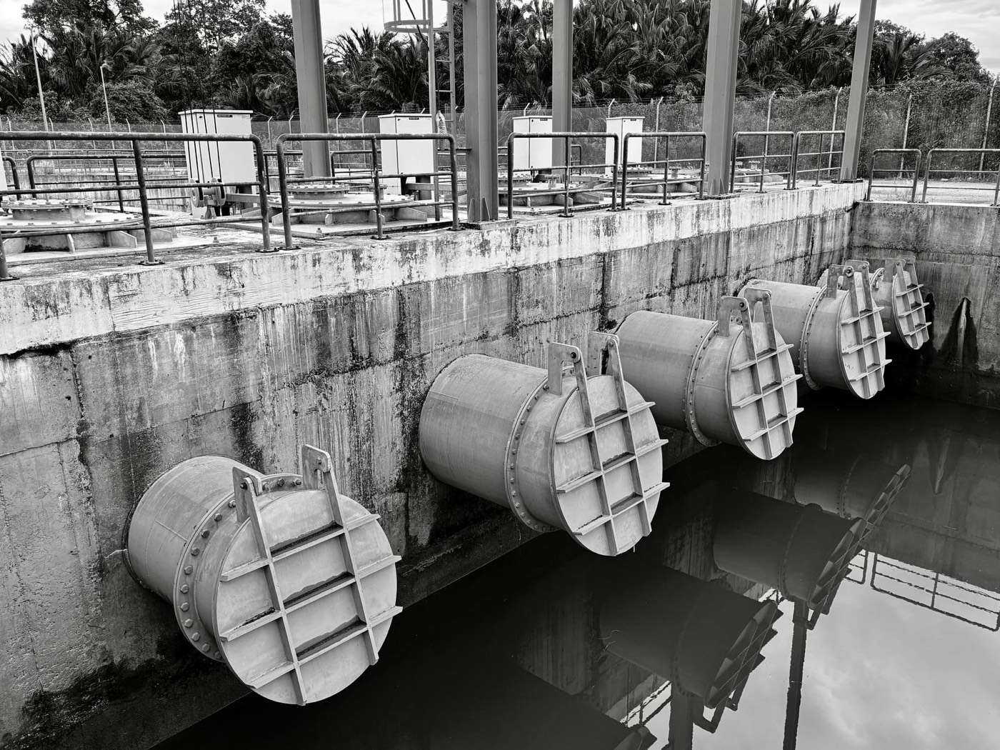 Concrete channel with flap gates at a water pump station, in black and white