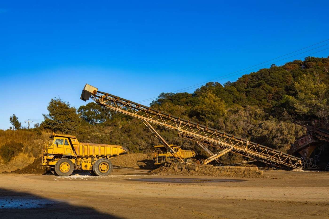 Dump truck beside a stacking conveyor at a quarry stockpile
