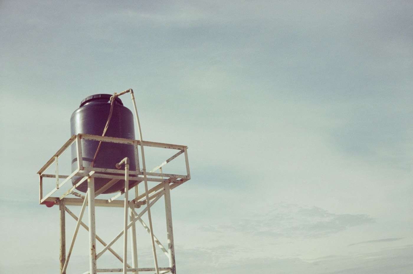 Water tank on a steel stand against a grey sky